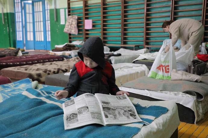 07 March 2022, Ukraine, Lviv: Little boy reads a newspaper in a gym where internally displaced persons have been placed in Lviv amid Russian invasion of Ukraine. Photo: Mykola Tys/SOPA Images via ZUMA Press Wire/dpa