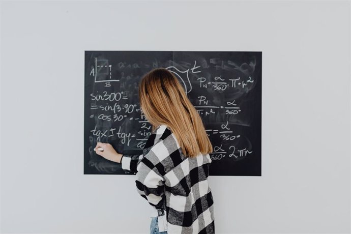 Una mujer escribe en una pizarra un problema de matemáticas