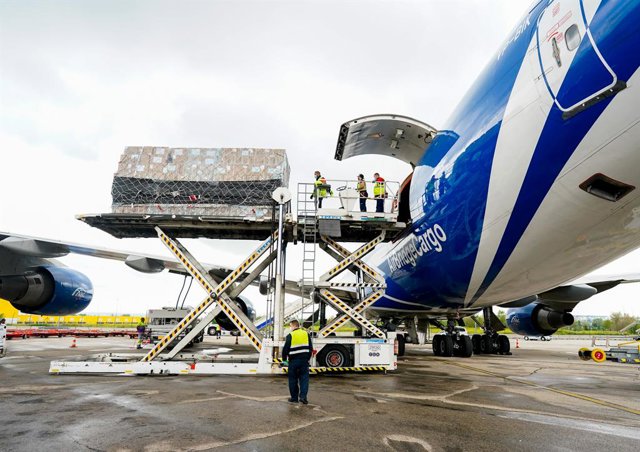 Archivo - Trabajadores del aeropuerto bajan carga de un avión en Barajas