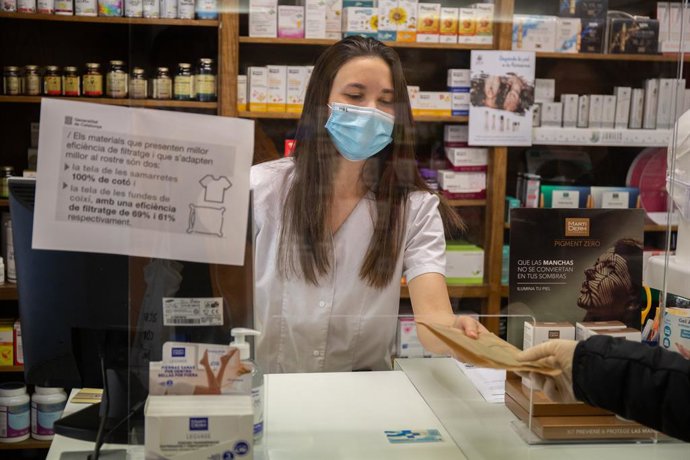Archivo - Una farmacutica entrega un producte.