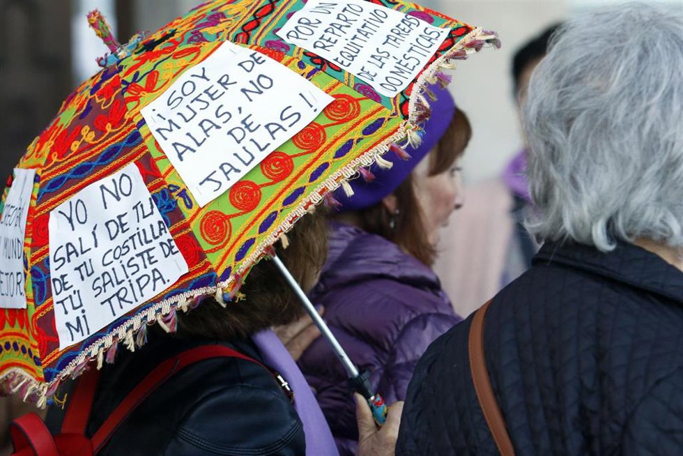 Archivo - Una mujer pega carteles reivindicativos en su paraguas durante la marcha por el Día Internacional de la Mujer en Málaga, foto de archivo