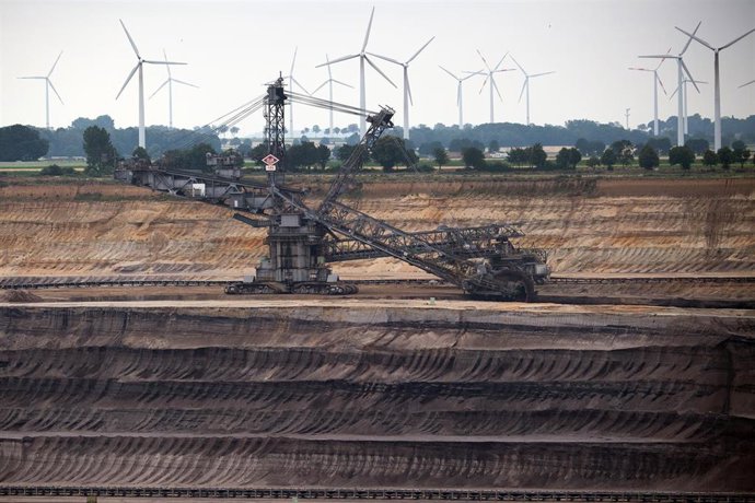 Archivo - 03 July 2020, North Rhine-Westphalia, Jackerath: Windmills rotate behind a bucket wheel excavator at the Garzweiler opencast lignite mine to generate electricity. Plans to phase out coal in Germany by 2038, including billions of euros in aid f
