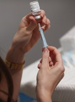 Archivo - Una profesional sanitaria sostiene una jeringuilla con un vial de la vacuna contra la COVID-19 
