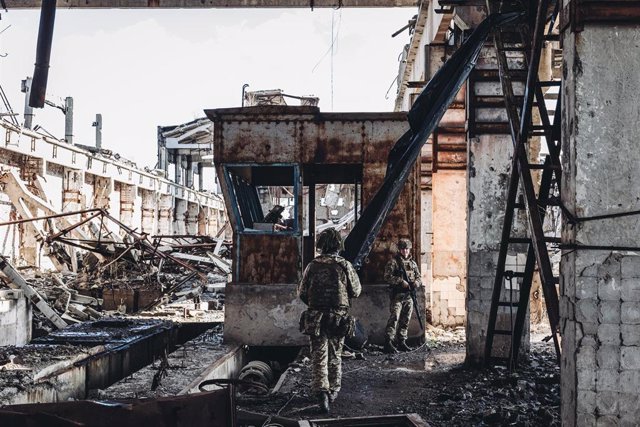 Dos soldados, del ejército ucraniano, caminan por una antigua fábrica destruida por la guerra en la línea del frente, a 19 de febrero de 2022, en Avdiivka, Oblast de Donetsk (Ucrania).