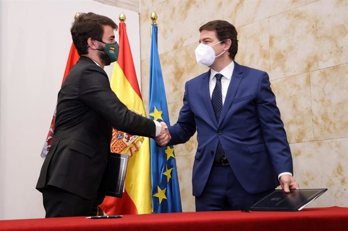 El líder de Vox en Castilla y León, Juan García-Gallardo (i) y el presidente en funciones de la Junta de Castilla y León, Alfonso Fernández Mañueco (d), se dan la mano tras la firma del pacto de Gobierno