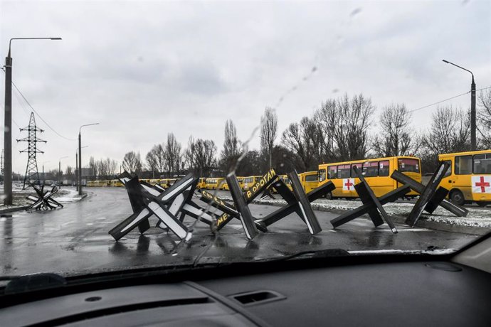 Autobuses para el desplazamiento de civiles en Ucrania junto a una barricada antitanques
