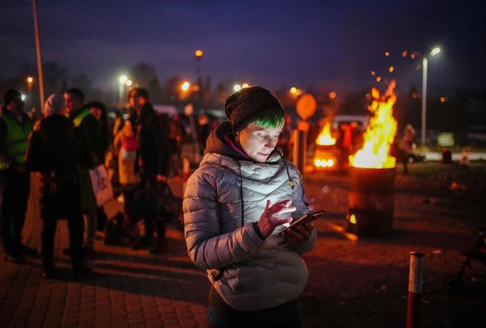 03 March 2022, Poland, Medyka: A journalist from Spain reads news on her smartphone at the Ukrainian-Polish border in Medyka. Numerous people arrive here every day, fleeing the war in Ukraine. Photo: Kay Nietfeld/dpa