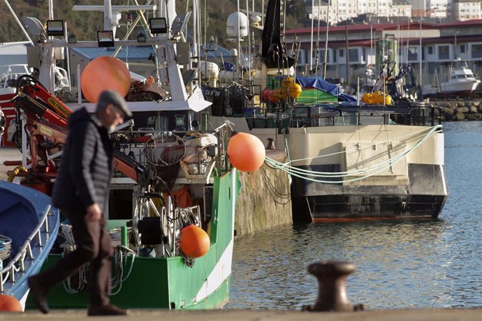 Una persona camina por el puerto de Celeiro, a 8 de marzo de 2022, en Viveiro, Lugo, Galicia (España). La flota de Celeiro, en el municipio lucense de Viveiro, ha iniciado un amarre parcial debido a la subida del precio del gasoil derivada de la guerra 