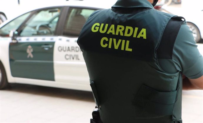Archivo - Un agente de la Guardia Civil, de espaldas, junto a un vehículo oficial, en imagen de archivo