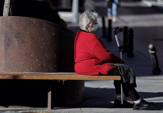 Archivo - Una mujer sentada con mascarilla, a 8 de febrero de 2022, en Madrid (España).