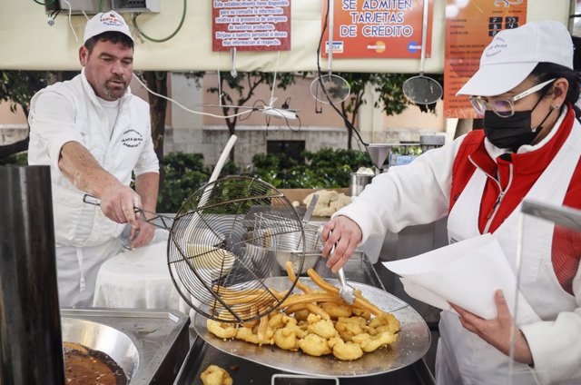Dos trabajadores hacen churros y buñuelos en las Fallas 2022, a 10 de marzo de 2022, en Valencia, Comunidad Valenciana (España).