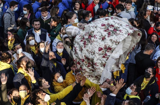 Un grupo de personas sujeta a una fallera en la Crida de las Falleras Mayores para dar comienzo a las Fallas en las Torres de Serrano, a 27 de febrero de 2022, en Valencia, Comunidad Valenciana (España). 