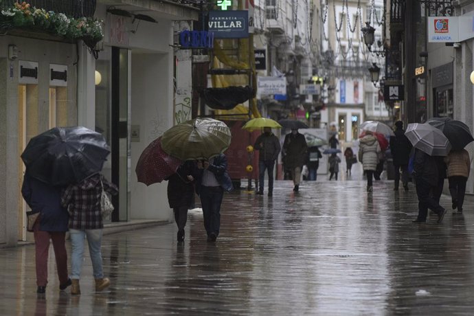 Archivo - Arxivo - Transeünts caminen protegits per una via de la Corunya, Galícia 