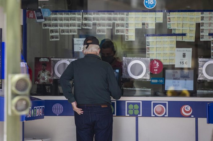 Archivo - Una persona comprando lotería en una administración.