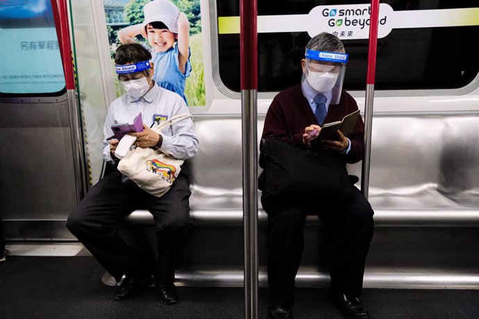 11 March 2022, China, Hong Kong: Commuters with face shields and masks ride a train in the subway. Hong Kong confirmed more than 29,000 new coronavirus infections. Photo: Keith Tsuji/ZUMA Press Wire/dpa