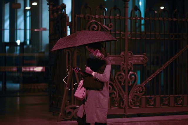 Archivo - Una persona camina bajo un paraguas junto al Ayuntamiento de Madrid un día marcado por una bajada de temperaturas y lluvias.