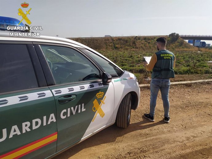 Agente de la Guardia Civil junto a su vehículo