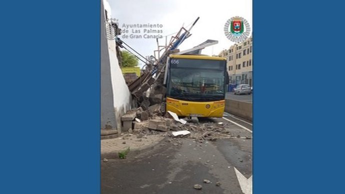 Un muro con valla publicitaria cae sobre una guagua