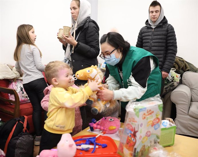 Voluntarias entregan juguetes a niños llegados de Ucrania, tras haber finalizado un viaje en autobús