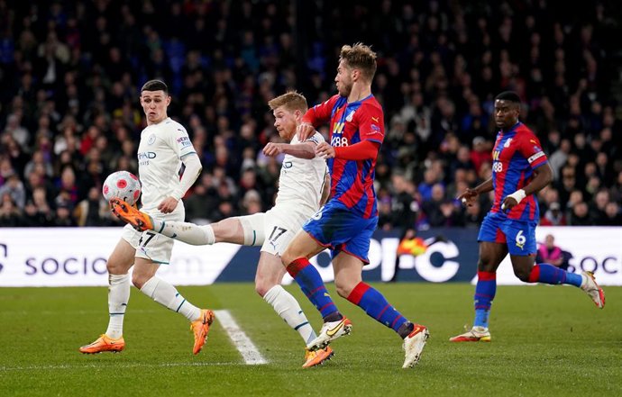14 March 2022, United Kingdom, London: Manchester City's Kevin De Bruyne shoots under pressure from Crystal Palace's Joachim Andersen during the English Premier League soccer match between Crystal Palace and Manchester City at Selhurst Park. Photo: Adam