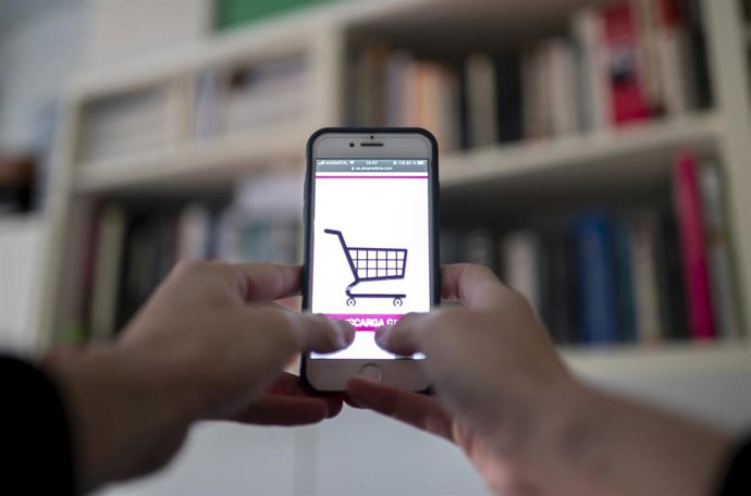 Archivo - Una persona compra a través de su teléfono móvil 