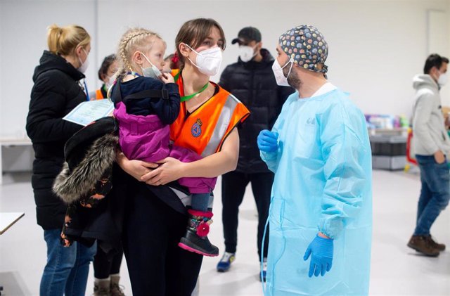 Una trabajadora sanitaria lleva en brazos a una niña procedente de Ucrania en las instalaciones del Hospital Enfermera Isabel Zendal