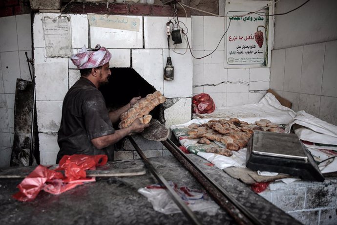 03 March 2022, Yemen, Sanaa: A Yemeni baker removes bread from the oven at a bakery in the city of Sanaa. Wheat prices have risen sharply on world markets in the wake of the Russian attack on Ukraine, putting more pressure on the already dire situation 