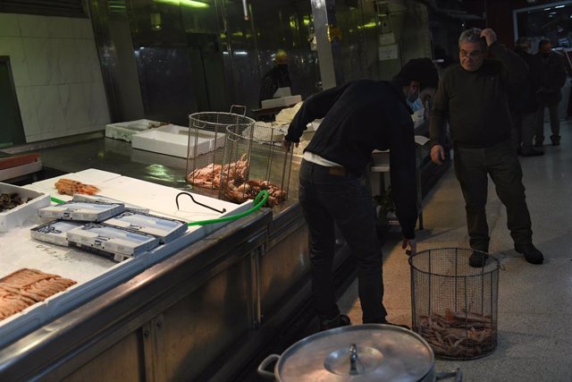 Archivo - Un pescadero madrileño traslada el marisco en una pescadería, a 23 de diciembre de 2021, en Madrid (España). Preparar el marisco mediante cocido forma parte de la cultura gastronómica de la Navidad.