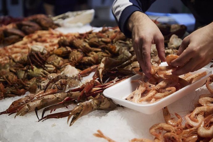 Archivo - Un vendedor de marisco, prepara una bandeja de gambas en una foto de archivo