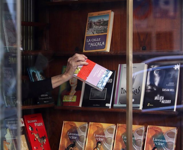 Archivo - La propietaria de una librería coloca libros en el escaparate de su librería