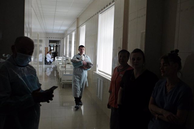 08 March 2022, Ukraine, Kiev: A man carries a newborn baby down the corridor of a maternity hospital functioning under martial law due to the Russian invasion. Photo: -/Ukrinform/dpa