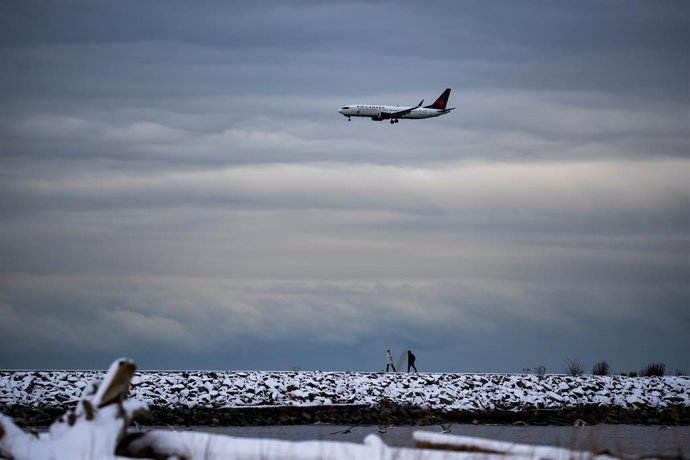 Archivo - 26 December 2021, Canada, Richmond: People walk on the Iona Jetty at Iona Beach Regional Park amid the cold weather as an Air Canada plane prepares to land at Vancouver International Airport. Photo: Darryl Dyck/The Canadian Press via ZUMA/dpa