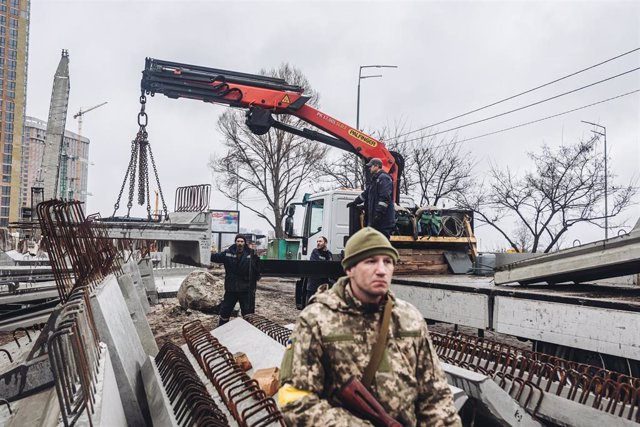 El 2 de marzo de 2022, en Kiev, Ucrania, varios trabajadores cargaron losas de concreto frente a una milicia ucraniana.