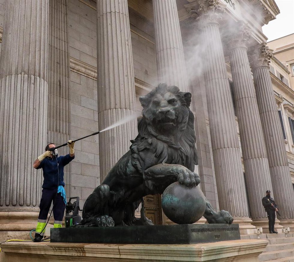 Un trabajador limpia el león del Congreso que está cubierto de polvo sahariano, a 15 de marzo de 2022, en Madrid (España).