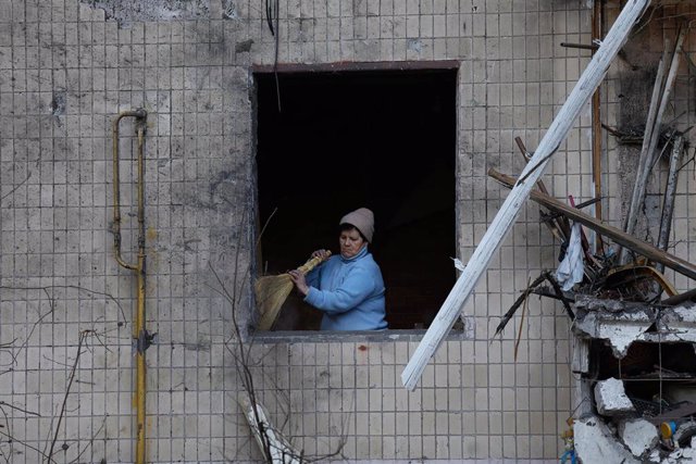 Una mujer limpia un inmueble dañado en Kiev
