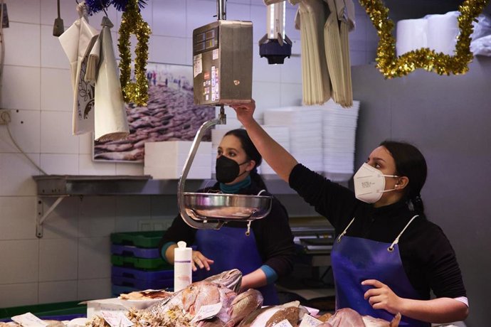 Archivo - Una vendedora pesa y marca el producto que un cliente le ha pedido en el Mercado de Triana, en foto de archivo.
