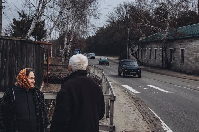 Unos civiles a las puertas de su casa observan la huida de cientos de vecinos, a 24 de febrero de 2022, en Oblast de Lugansk (Ucrania)