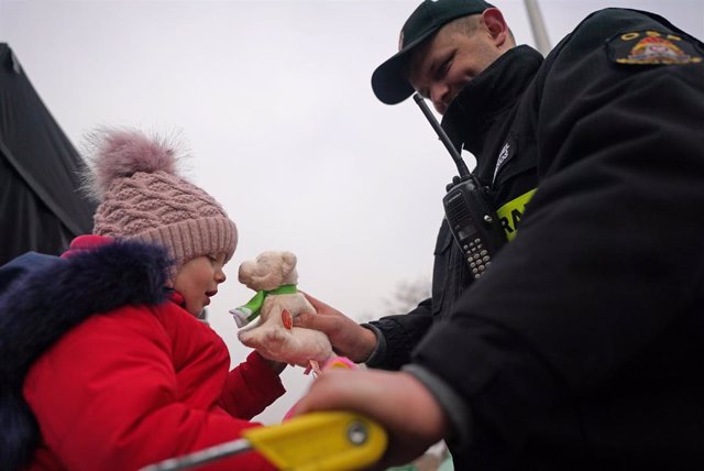 Un guardia ofrece un jugueta a un niño en Medyka (Polonia)