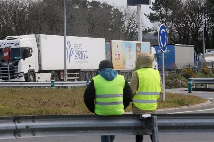 Dos miembros de un piquete observan los camiones estacionados en una rotonda durante el cuarto día de paros en el sector de los transportes.