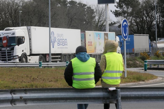 Dos miembros de un piquete observan los camiones estacionados en una rotonda de O Corgo, durante el cuarto día de paros en el sector de los transportes, a 17 de marzo de 2022, en O Corgo, Lugo, Galicia (España). Los transportistas siguen este jueves el 