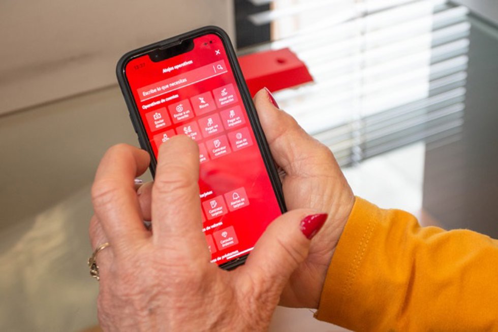 Una persona mayor utiliza una aplicación bancaria en un teléfono móvil