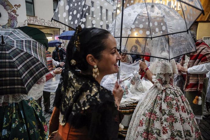 Una fallera se cubre con un paraguas en la ofrenda floral a la Virgen de los Desamparados, a 17 de marzo de 2022, en Valencia, Comunidad Valenciana (España). La Junta Central Fallera ha decidido celebrar el desfile de esta tarde, pese al temporal de llu