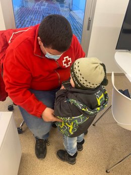 Un trabajador de Cruz Roja Extremadura atiende a un niño procedente de Ucrania.