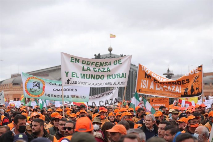 Varios manifestantes, con gorras naranjas y pancartas en defensa de la caza, en la marcha 20M, a 20 de marzo de 2022, en Madrid (España). 