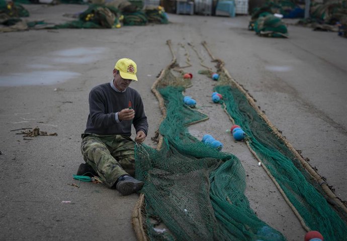 Archivo - Un pescador remienda sus redes de pesca en la Lonja pesquera de la Cofradía de Pescadores en el Puerto de Bonanza, Sanlúcar de Barrameda, Cádiz, (Andalucía, España), a 31 de marzo, de 2020. (Foto de archivo).