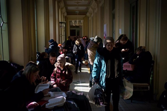 19 March 2022, Poland, Przemysl: Families from Ukraine sit and wait with their luggage in a corridor at Poland's Przemysl train station. Photo: Victoria Jones/PA Wire/dpa