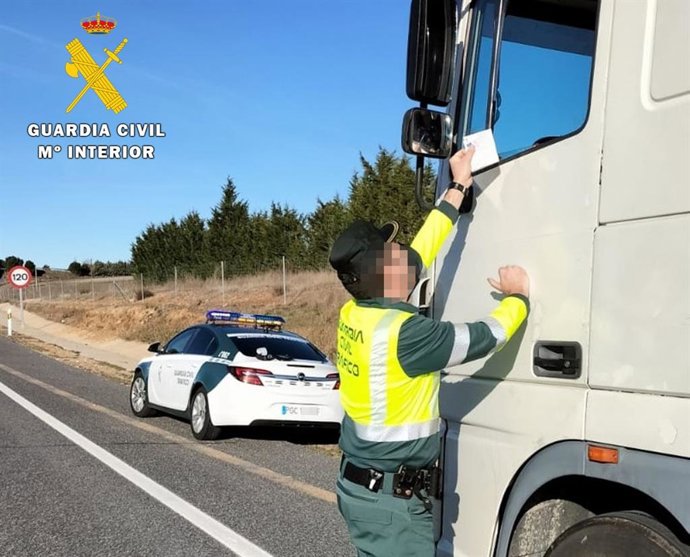 Un agente de la Guardia Civil inspecciona la tarjeta del tacógrafo de uno de los camioneros.