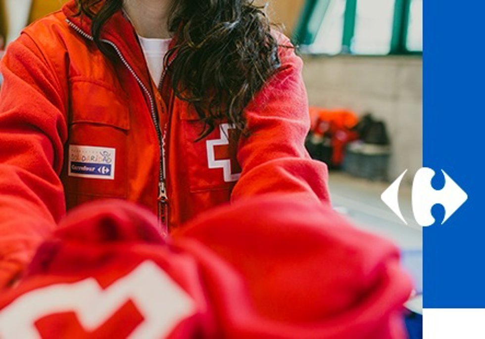 Una voluntaria entrega un chaleco de Cruz Roja
