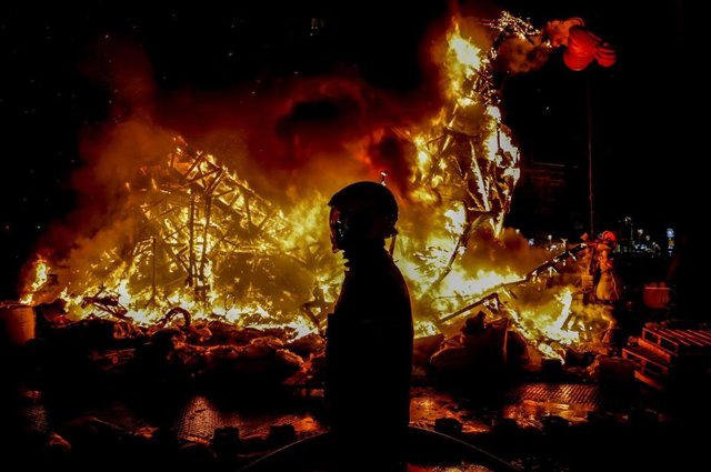 Un bombero frente a una falla,  quemándose, durante la Cremá