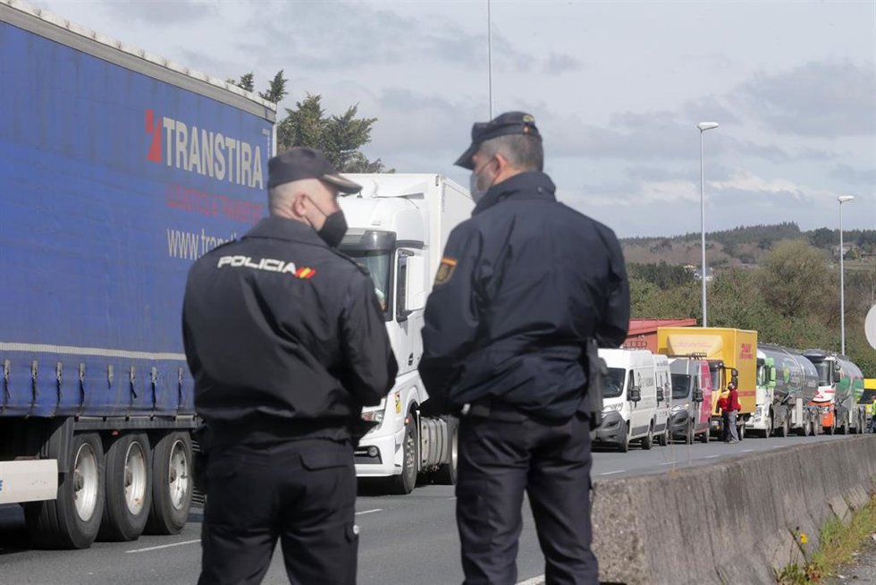 Agentes de Policía Nacional observan los camiones parados en el arcén en uno de los accesos al Polígono de O Ceao,en Lugo